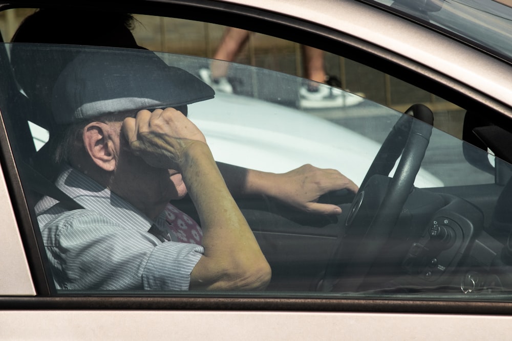 homme en chemise boutonnée à carreaux blanc et noir conduisant une voiture