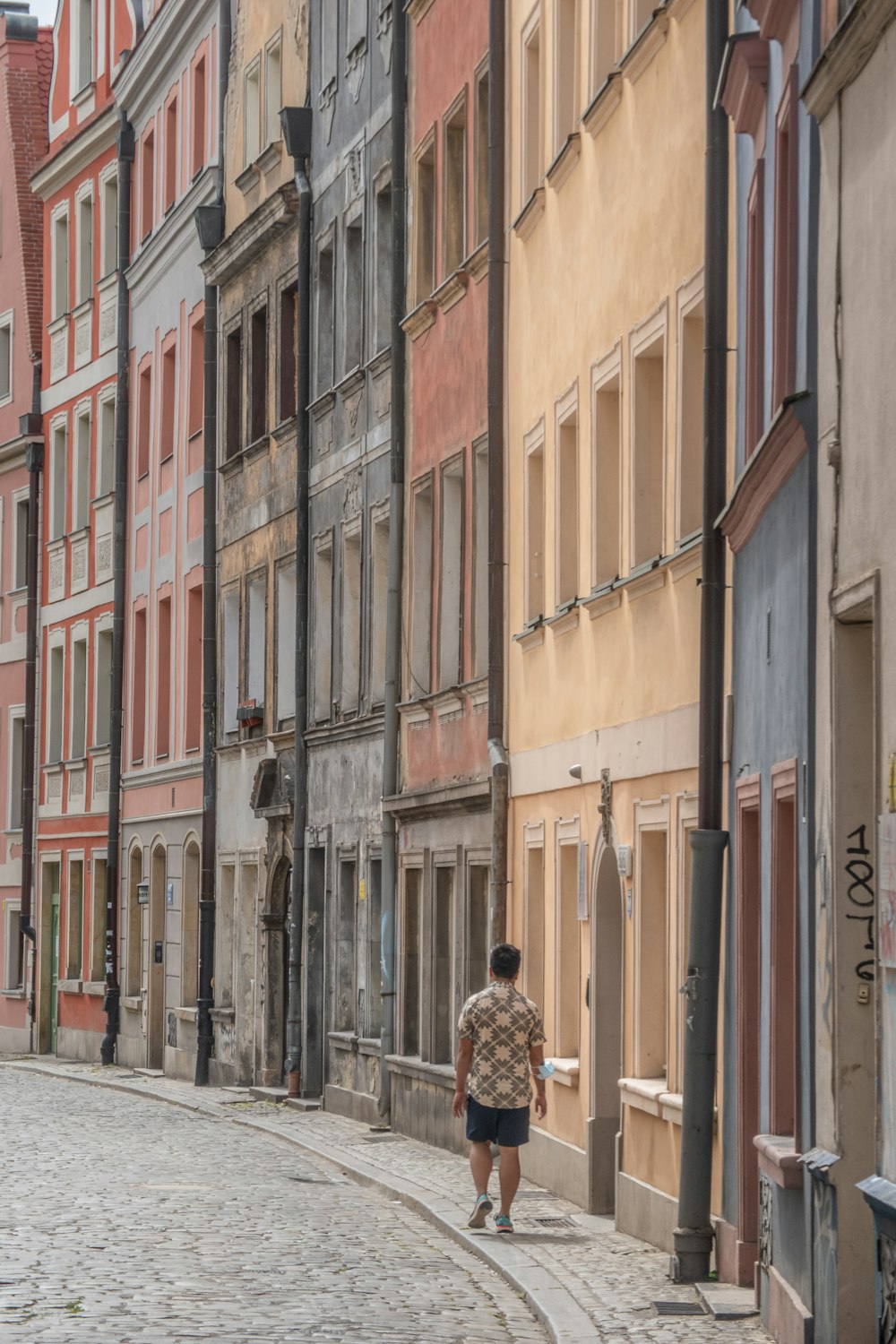 woman in brown coat walking on sidewalk during daytime