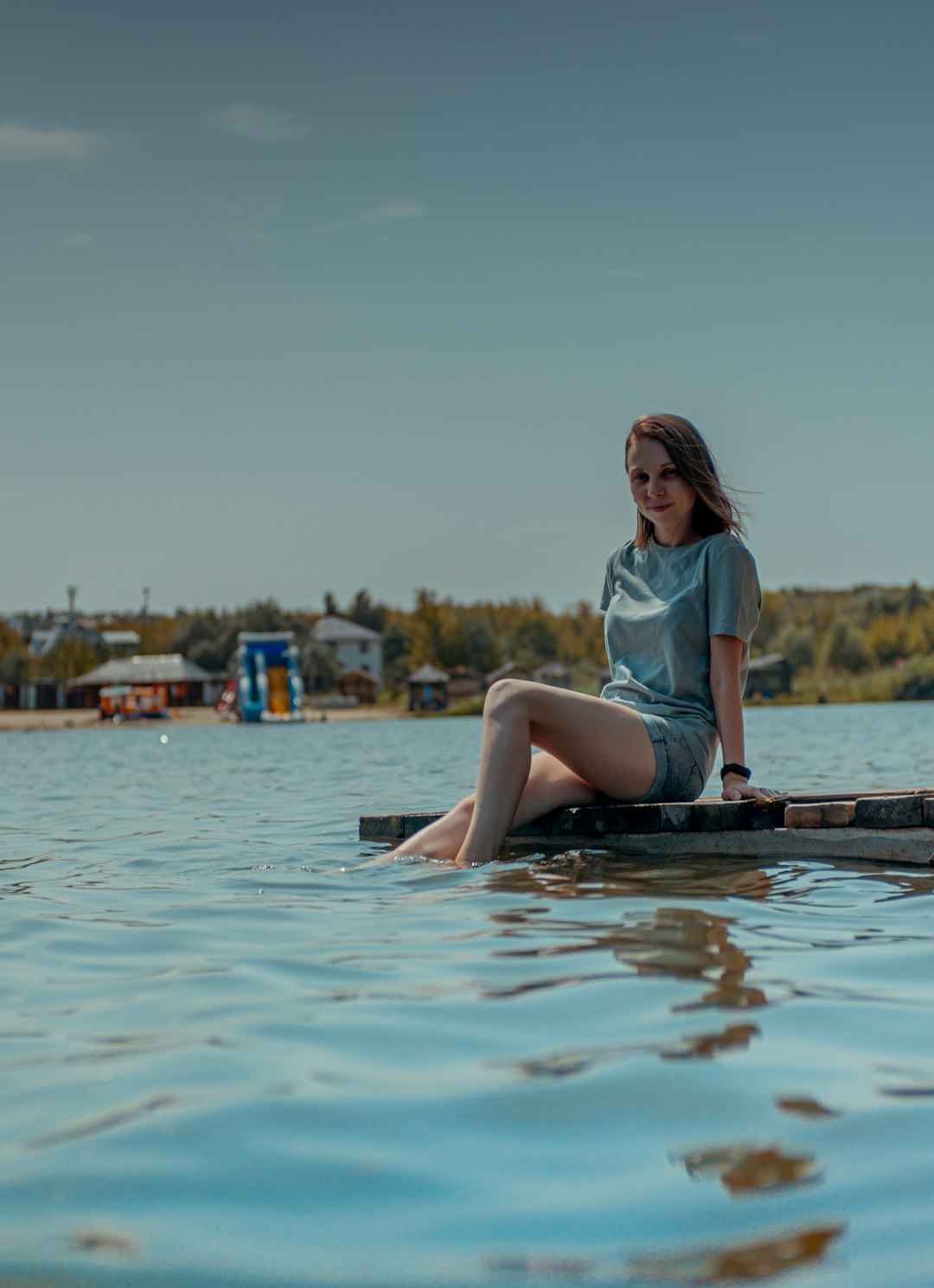 woman in white shirt sitting on brown wooden dock during daytime