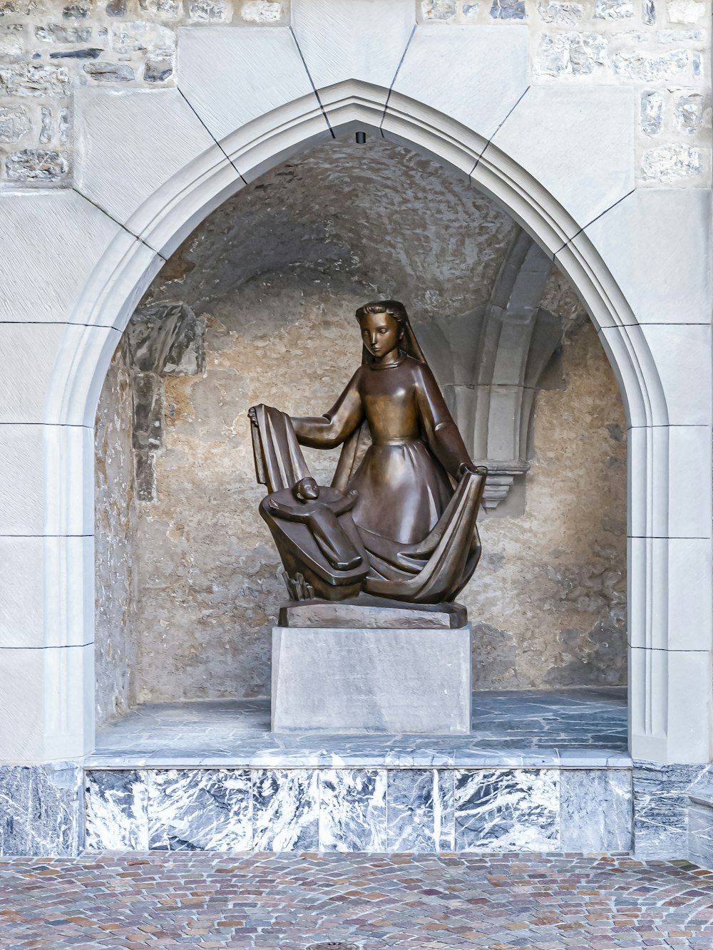 statua marrone su muro di cemento grigio