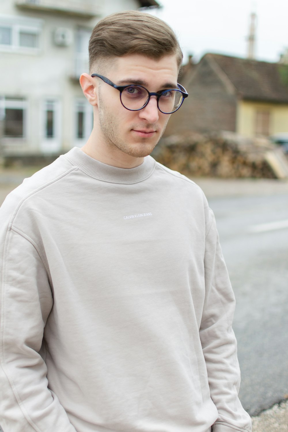 Mann im weißen Rundhalspullover mit schwarz gerahmter Brille