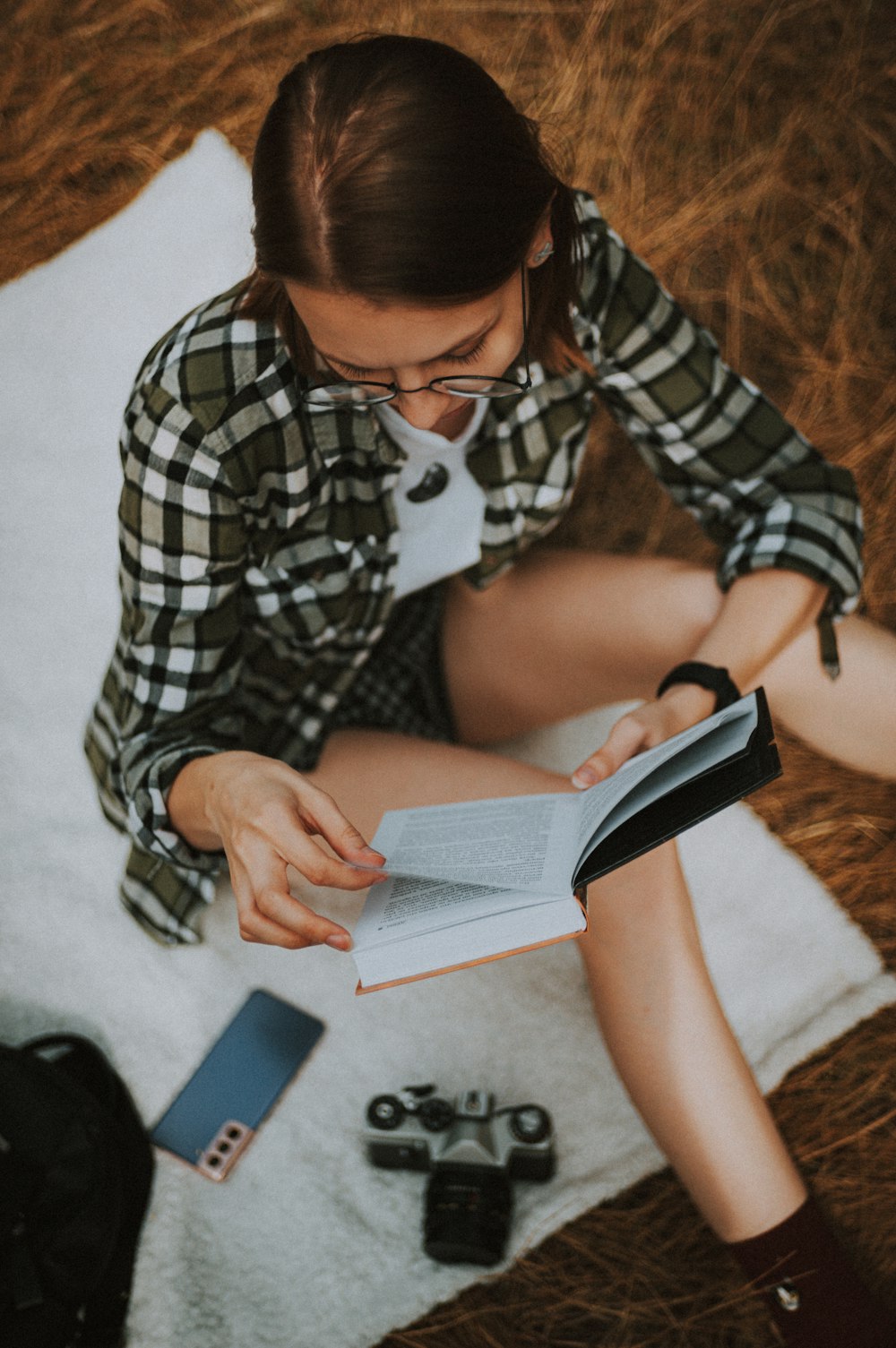 woman in black and white plaid dress shirt holding black smartphone