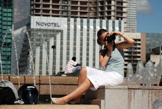 woman in white dress shirt and white shorts sitting on concrete bench