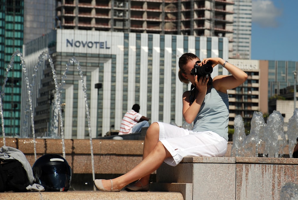 woman in white dress shirt and white shorts sitting on concrete bench