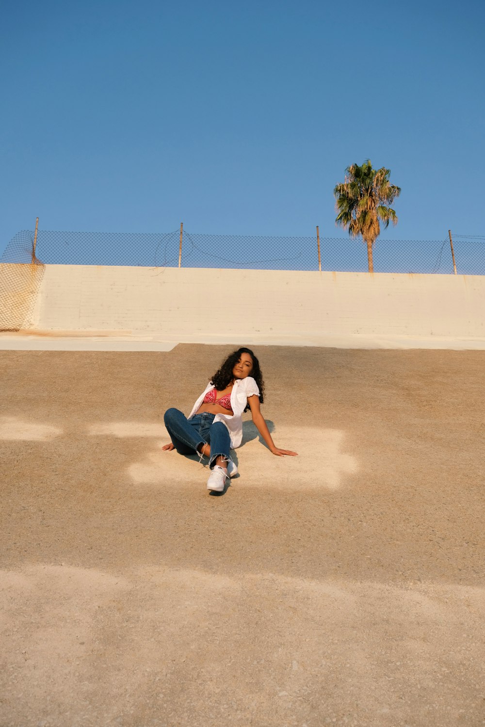 woman in black shirt and pants sitting on brown sand during daytime