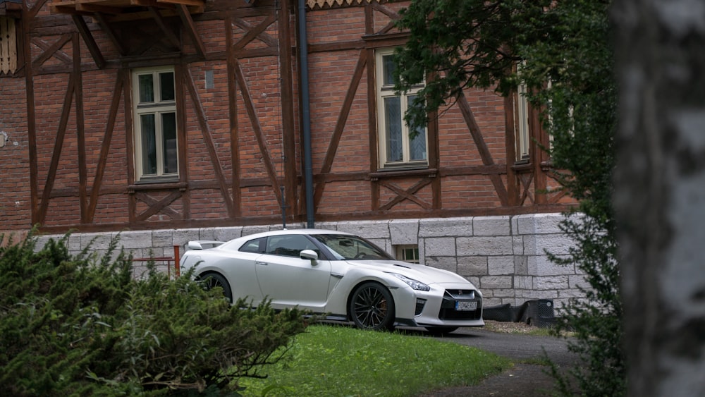 white coupe parked beside brown concrete building during daytime