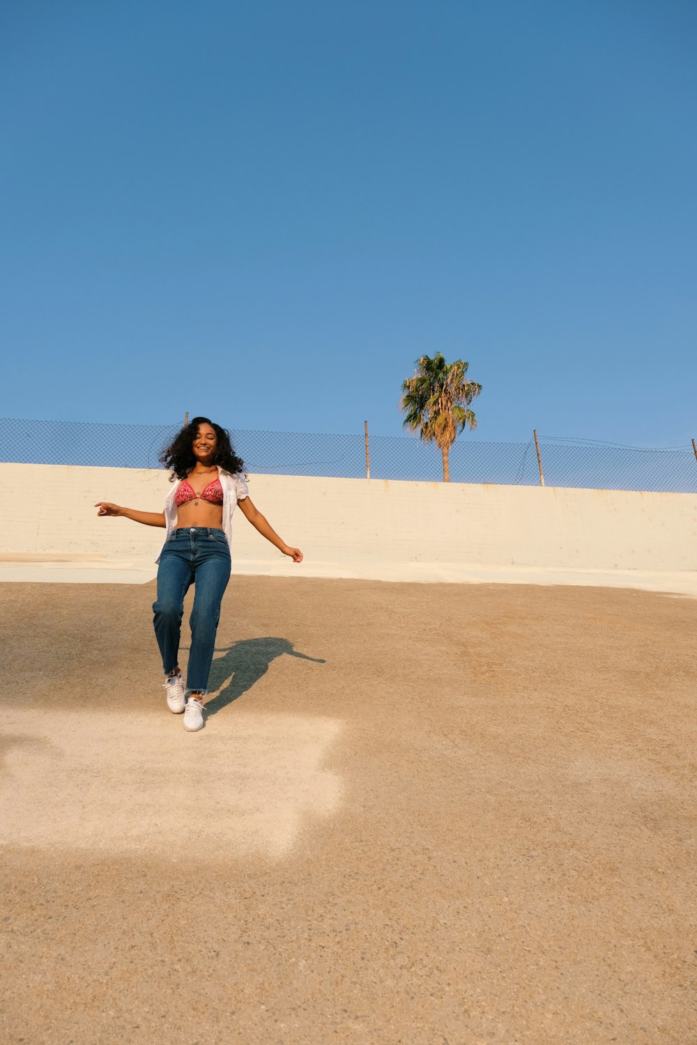 Mujer en jeans de mezclilla azul caminando sobre arena marrón durante el día