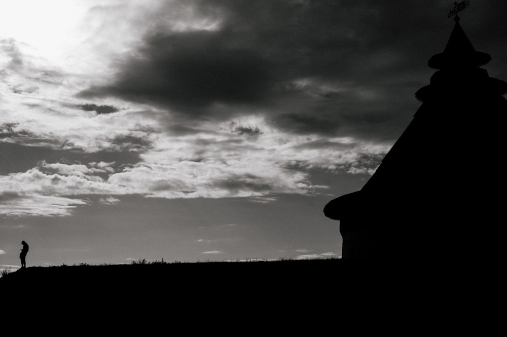 silhouette of man standing under cloudy sky during daytime