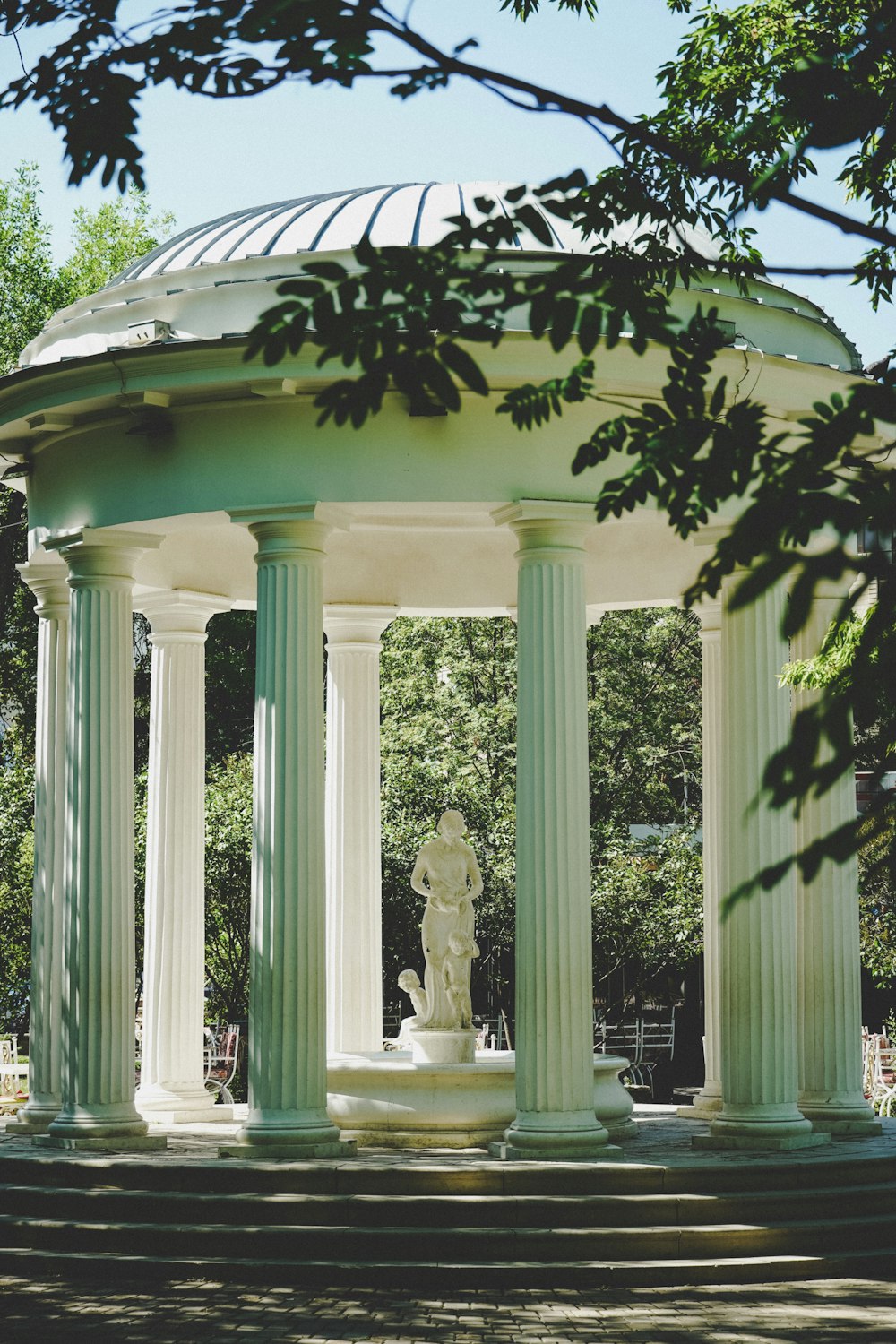 white concrete statue near green trees during daytime