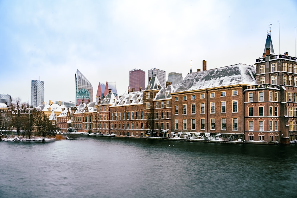 brown and white concrete buildings beside river under white sky during daytime