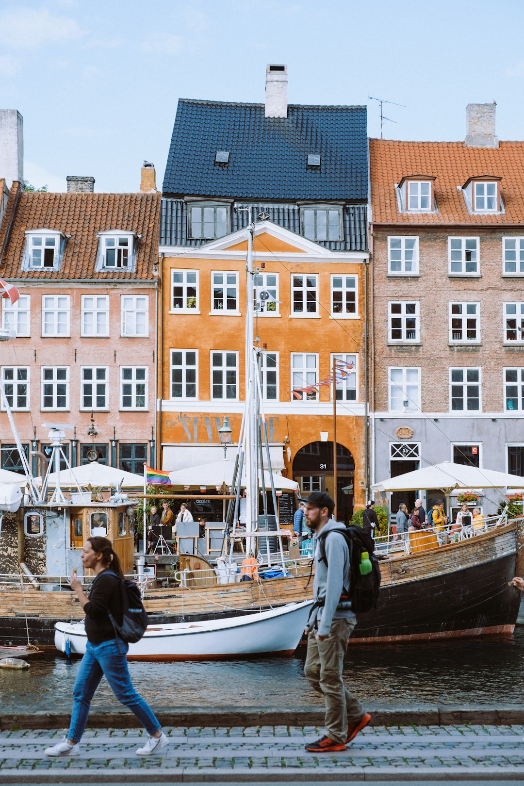 man in black jacket standing beside white and brown boat during daytime