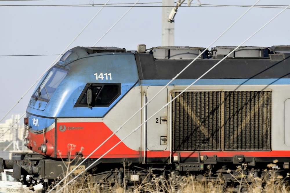 red and blue train on rail tracks during daytime