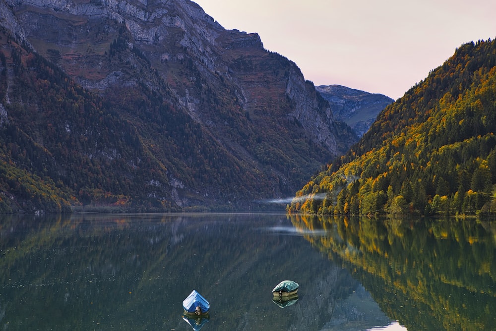 white and blue boat on lake near mountain during daytime