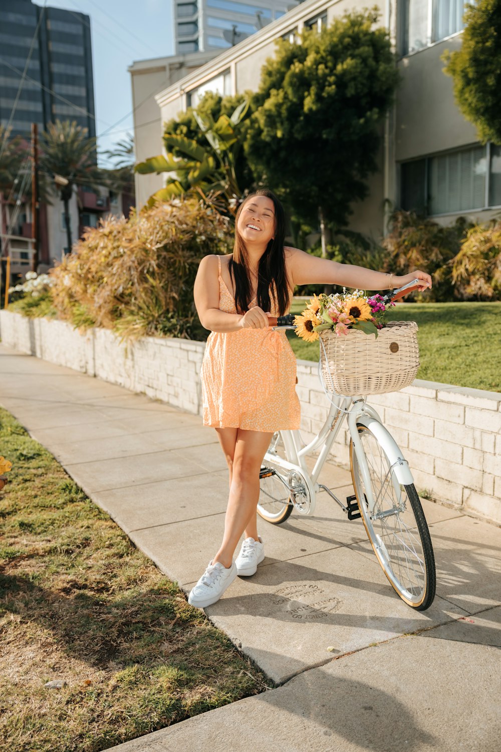 woman in brown dress holding basket of fruits standing on sidewalk during daytime