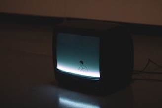 black crt tv turned on on brown wooden table