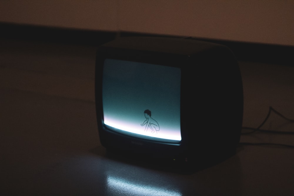 Schwarzer CRT-Fernseher auf braunem Holztisch eingeschaltet