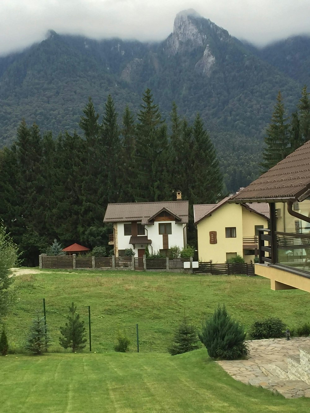 white and brown house near green trees and mountain during daytime