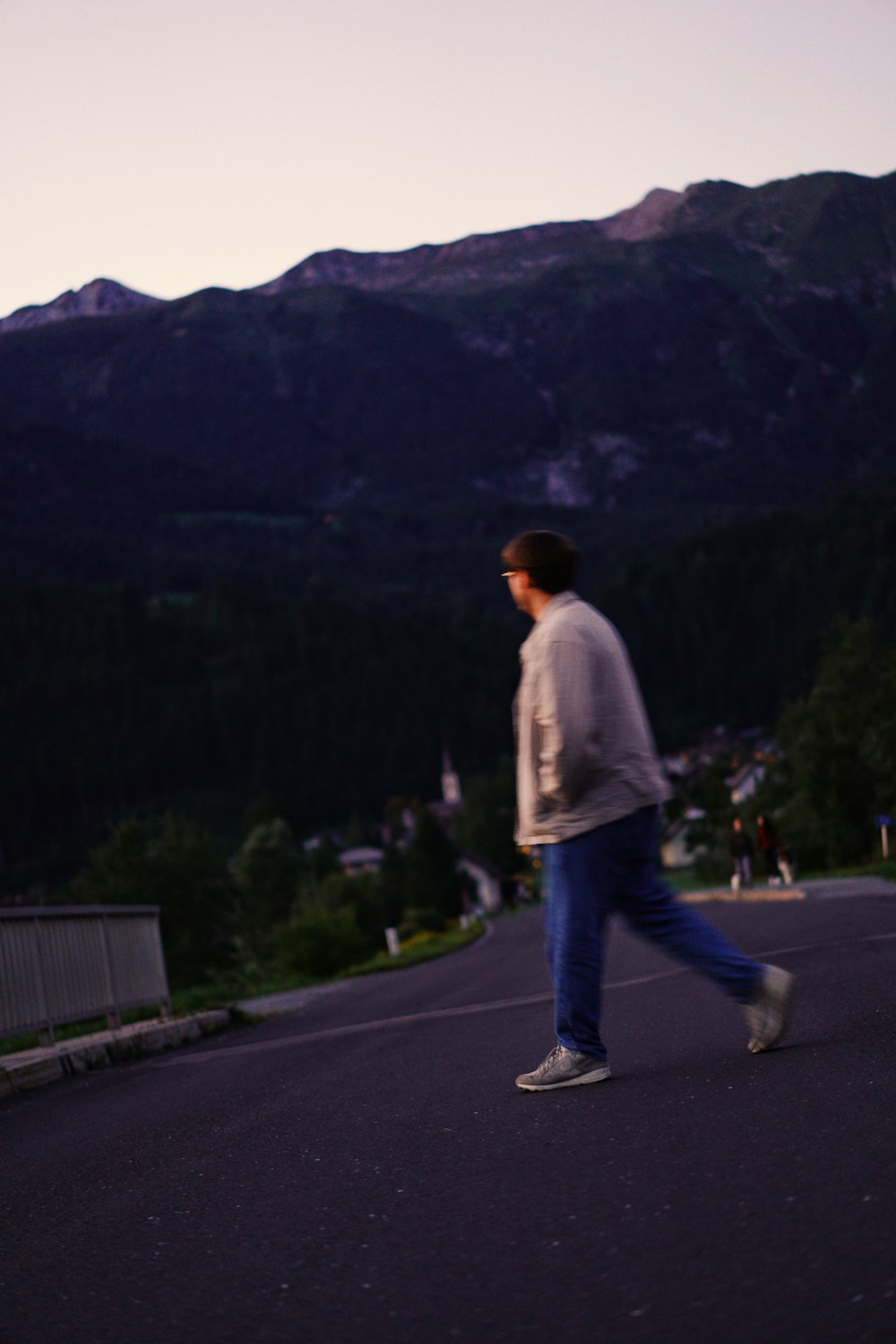 Uomo in camicia bianca e jeans blu in denim in piedi sulla strada di cemento grigia durante il giorno