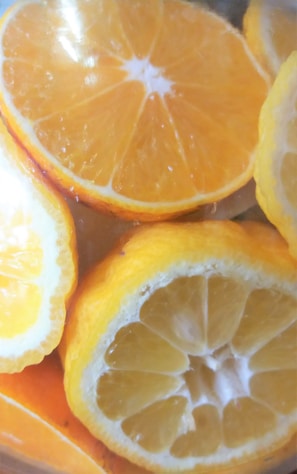Several slices of citrus fruits, including oranges and lemons, are overlapping each other. The slices are vibrant in color, with visible textures and details of the fruit flesh and rind.