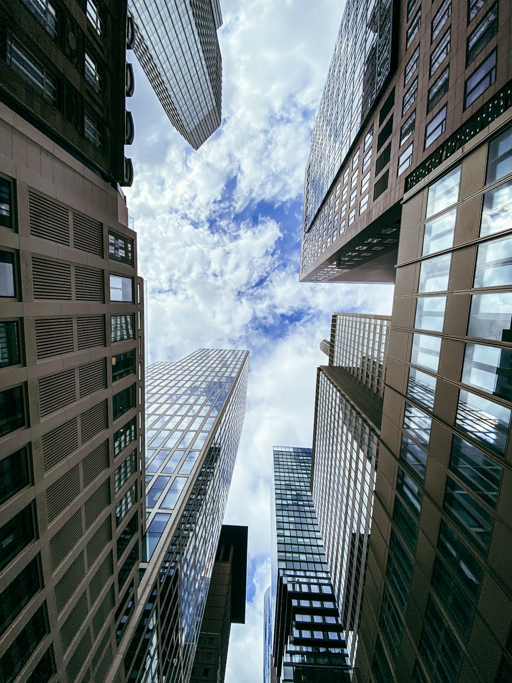 low angle photography of high rise buildings under blue sky and white clouds during daytime