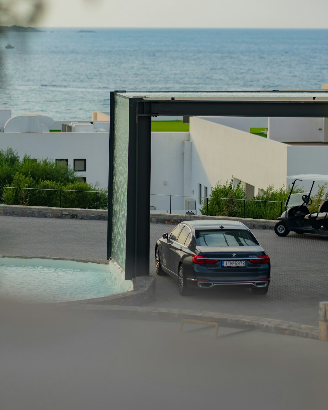 black sedan parked beside white concrete building during daytime