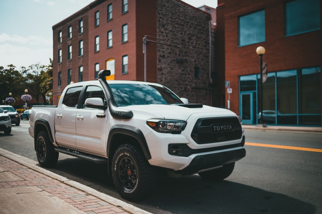 white chevrolet crew cab pickup truck parked beside brown concrete building during daytime