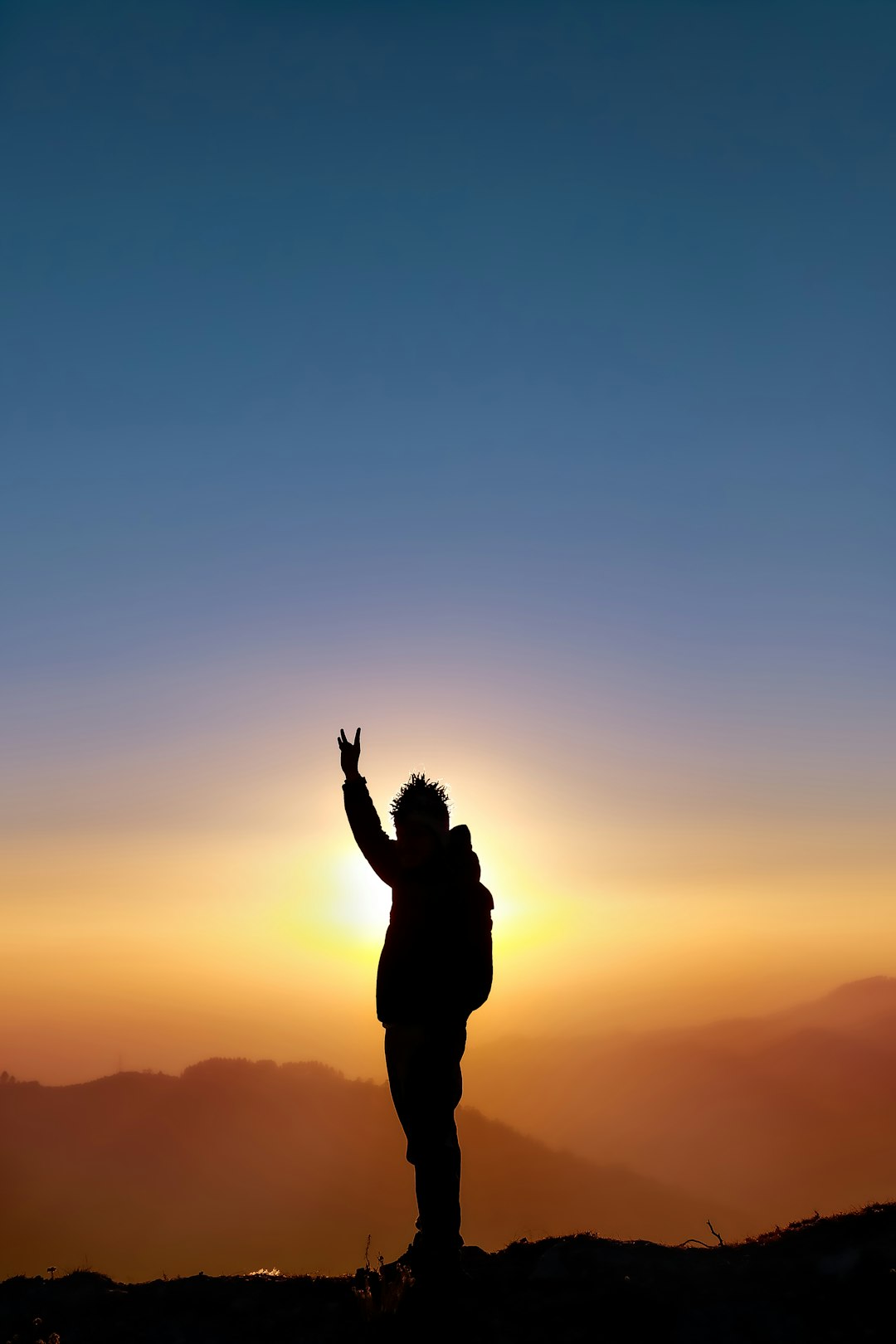 silhouette of man raising his hands during sunset