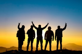 silhouette of people raising their hands