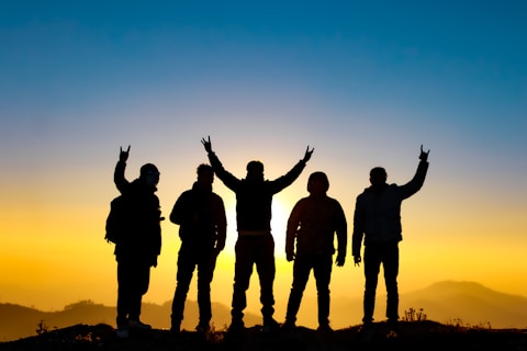 silhouette of people raising their hands