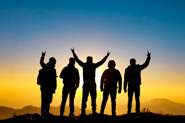silhouette of people raising their hands