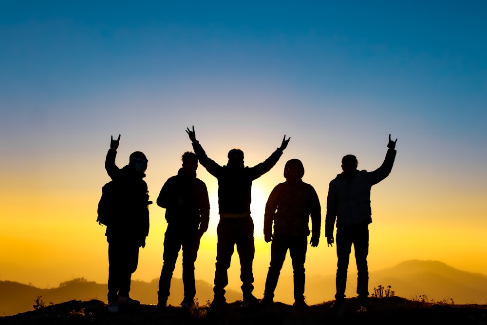 silhouette of people raising their hands