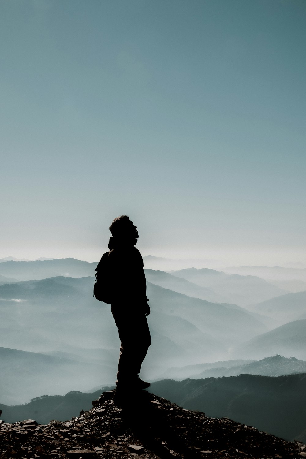 silhouette of man standing on top of mountain during daytime