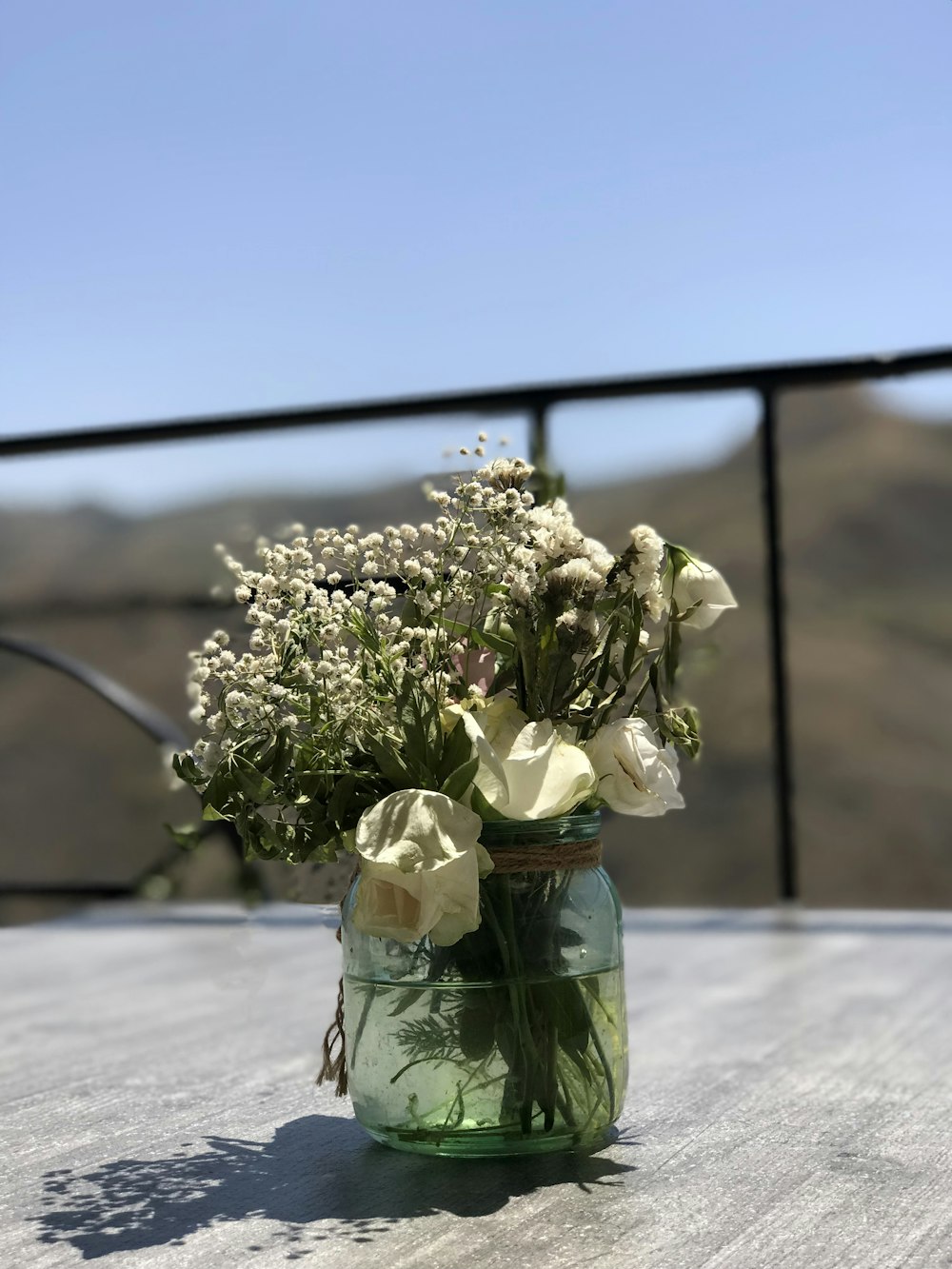 white flowers in green glass vase