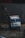 A large, colorful truck with various inscriptions and decorations is navigating a rough, dirt path on a foggy day. The words 'ROAD KING' are prominently displayed on the bumper, and the truck appears to be traveling in a mountainous region surrounded by dark, rocky terrain.