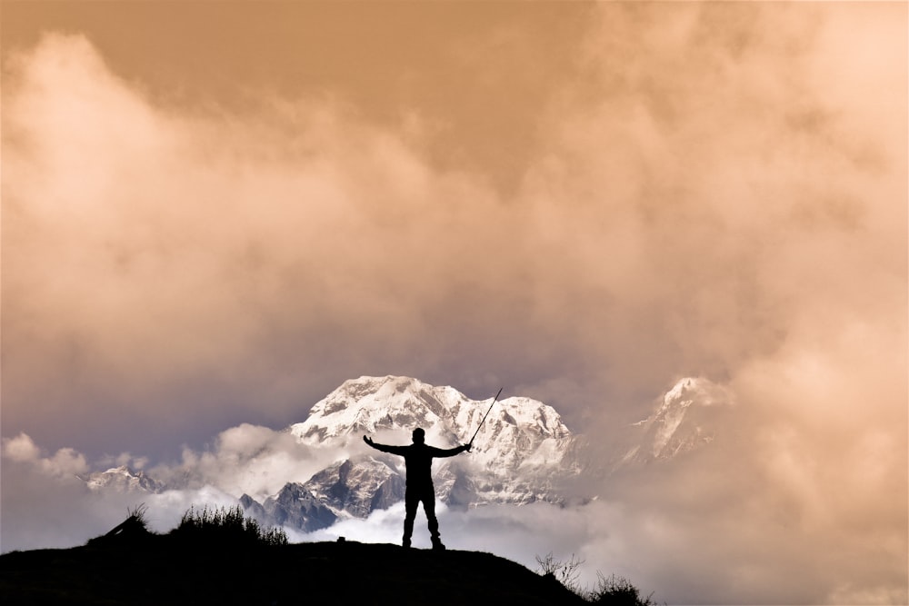 silhouette of man standing on rock formation during sunset