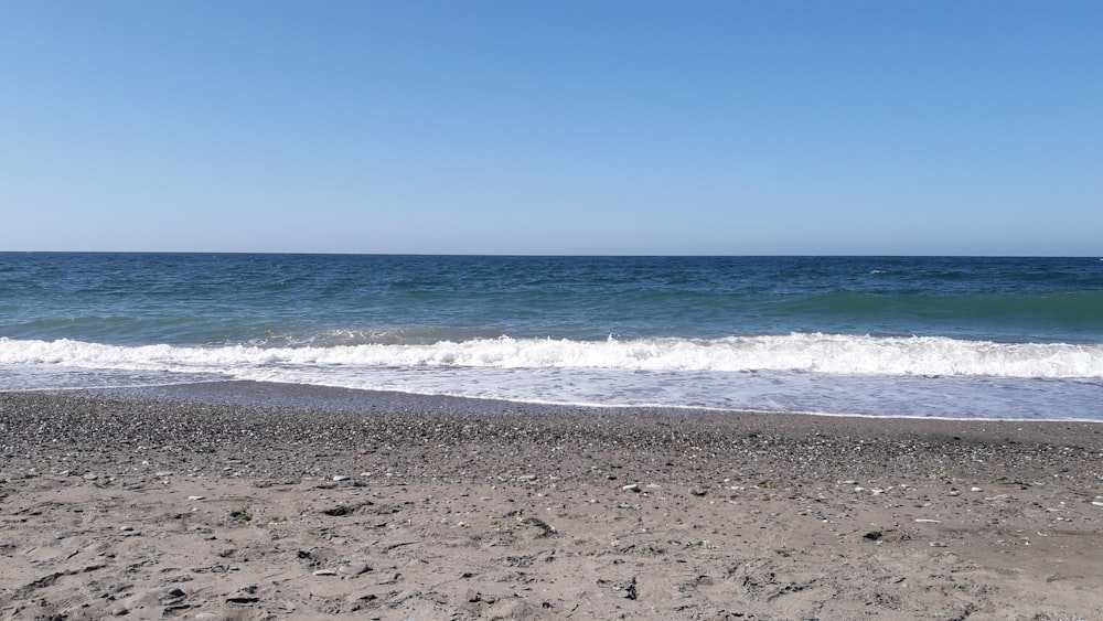 sea waves crashing on shore during daytime