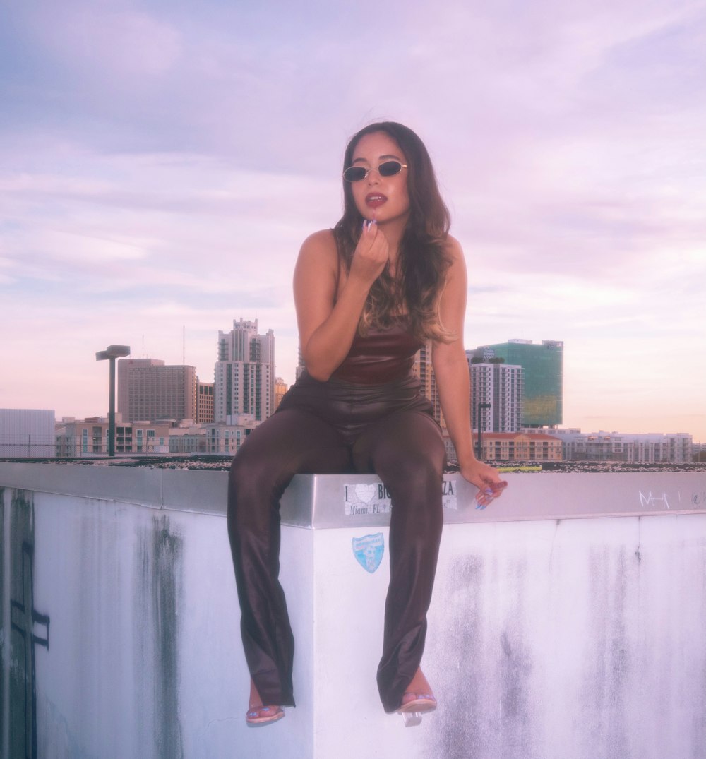 woman in brown tank top and blue denim jeans standing on water fountain during daytime