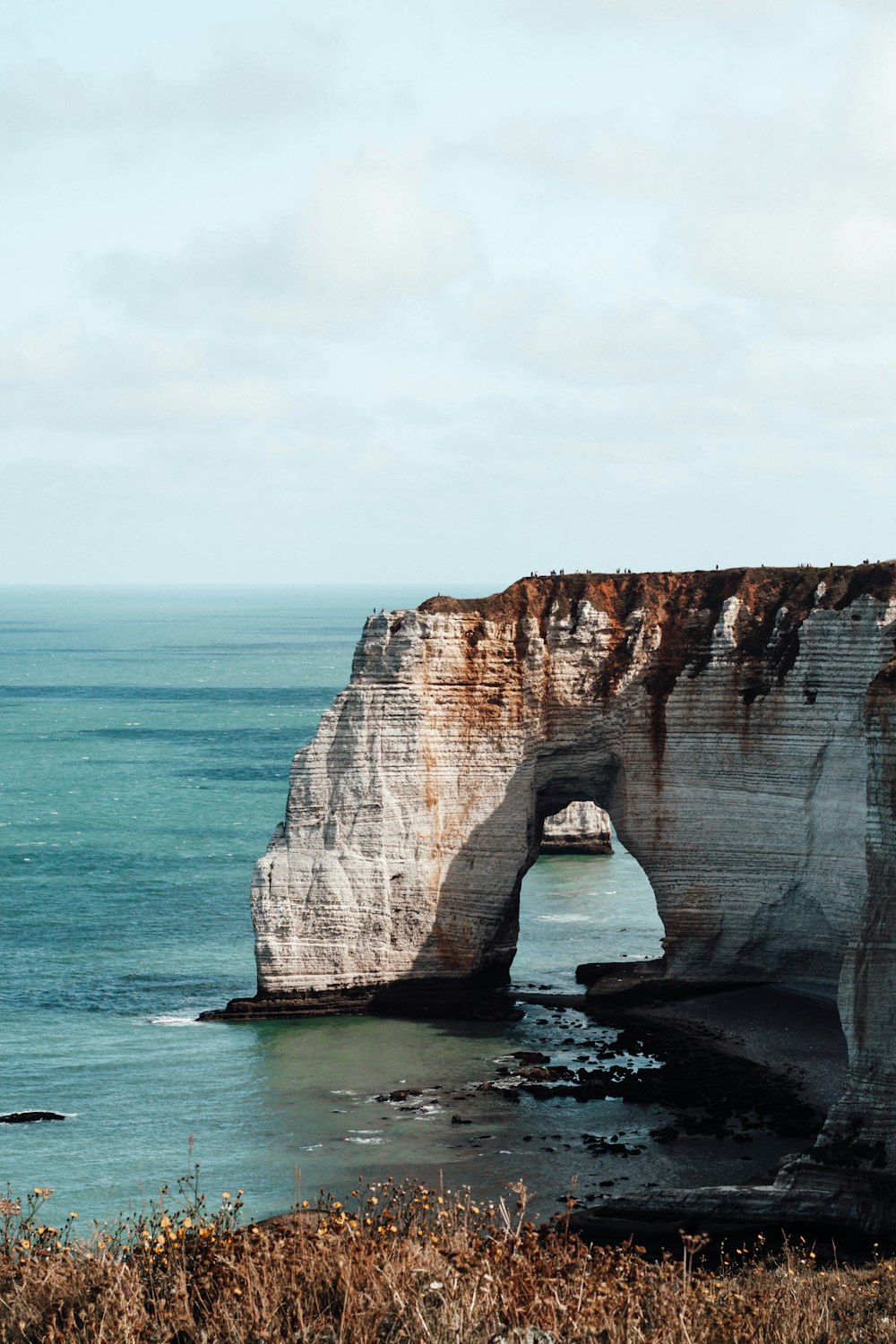 brown rock formation on sea under white sky during daytime