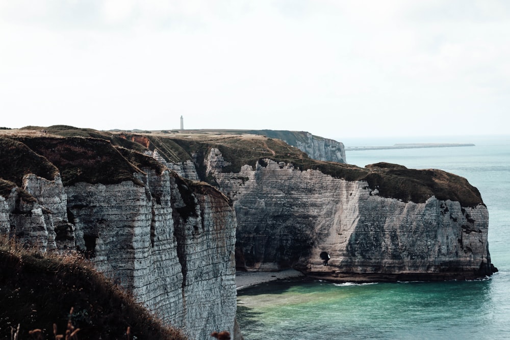 person standing on cliff near body of water during daytime