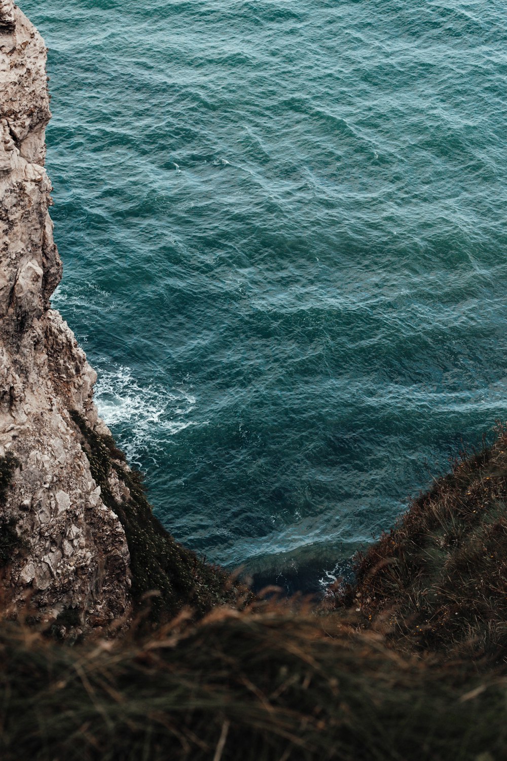 blue sea beside brown rocky mountain during daytime