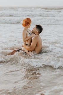 man and woman kissing on beach during daytime