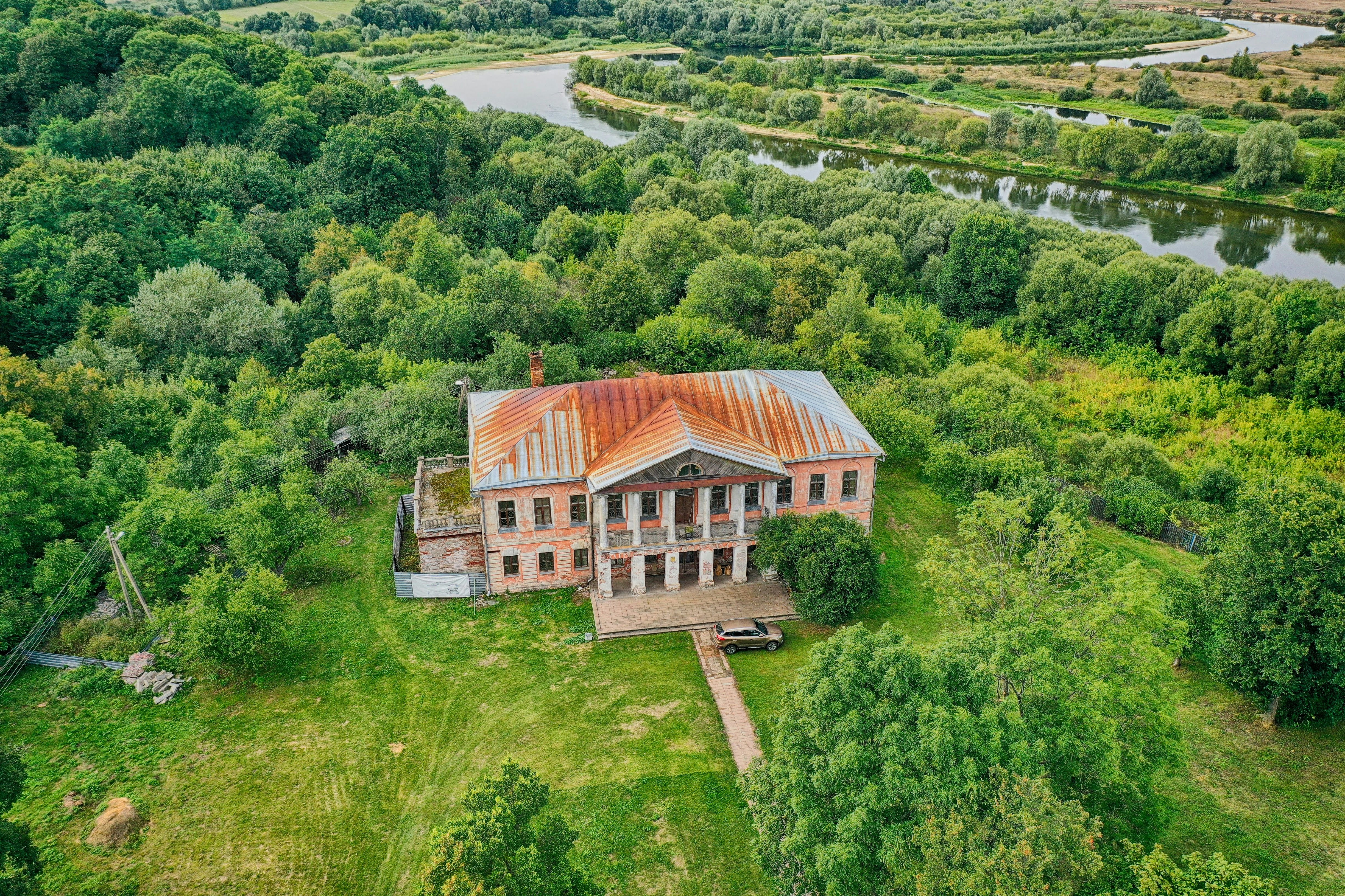 brown and white house surrounded by green trees during daytime