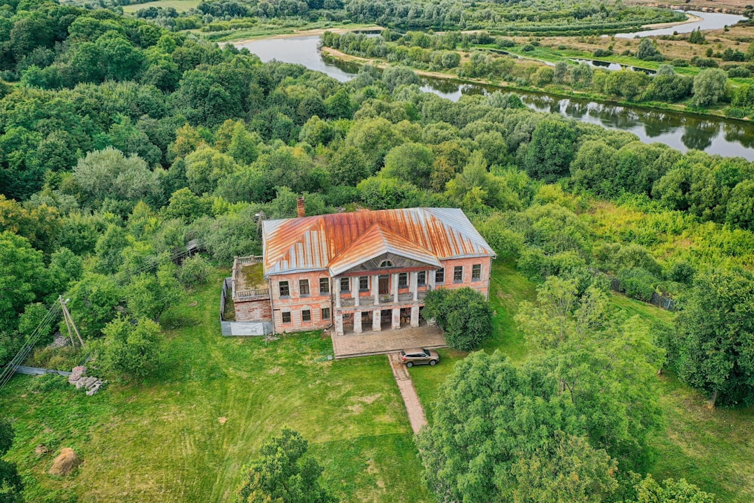 brown and white house surrounded by green trees during daytime