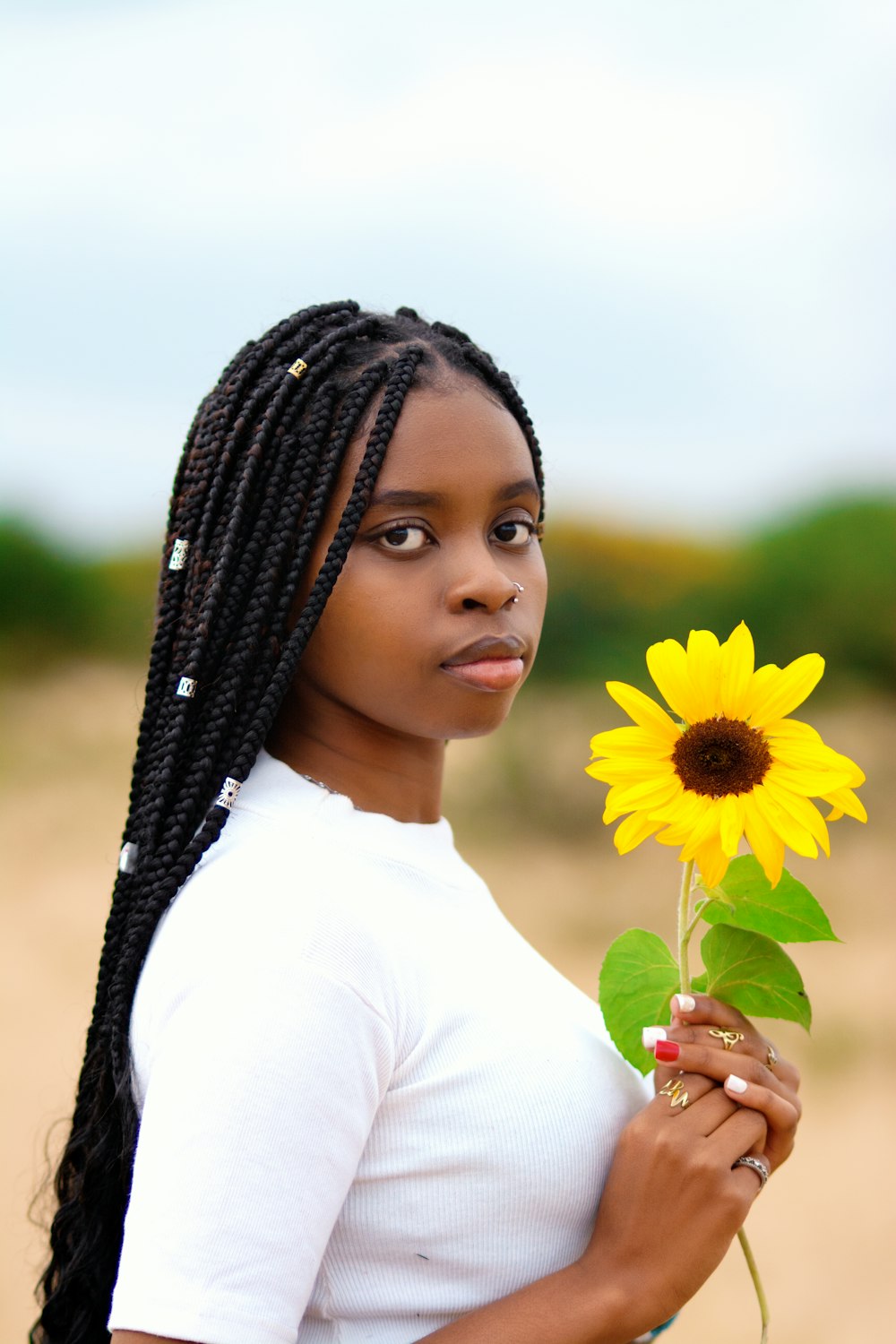 woman in white shirt holding yellow sunflower during daytime