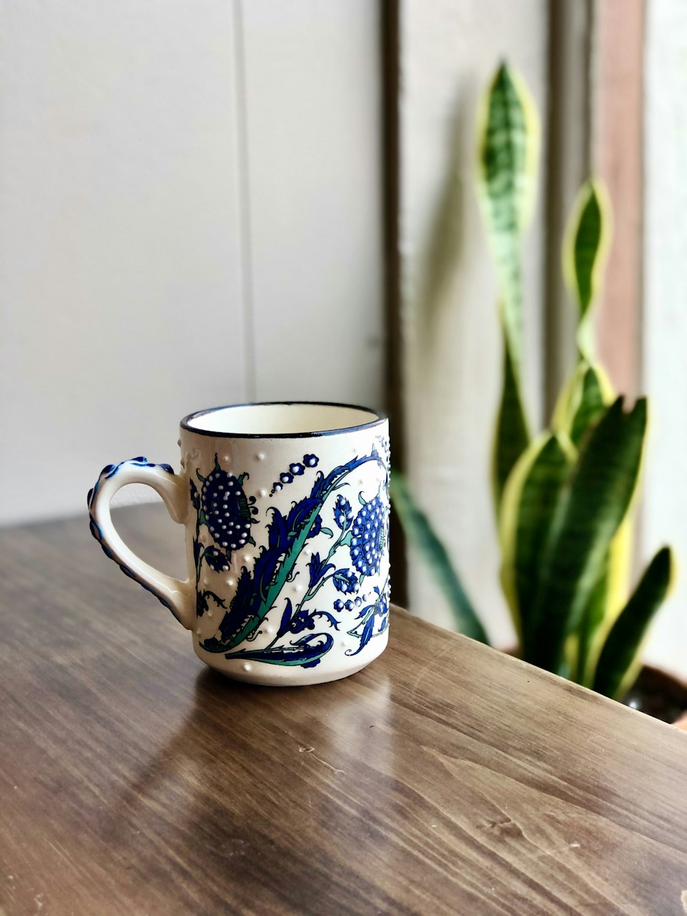 white blue and green floral ceramic mug on brown wooden table