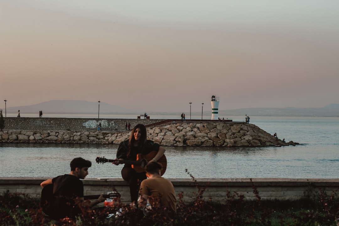 people sitting on concrete bench near sea during daytime