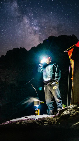man in black jacket and blue denim jeans standing on orange tent