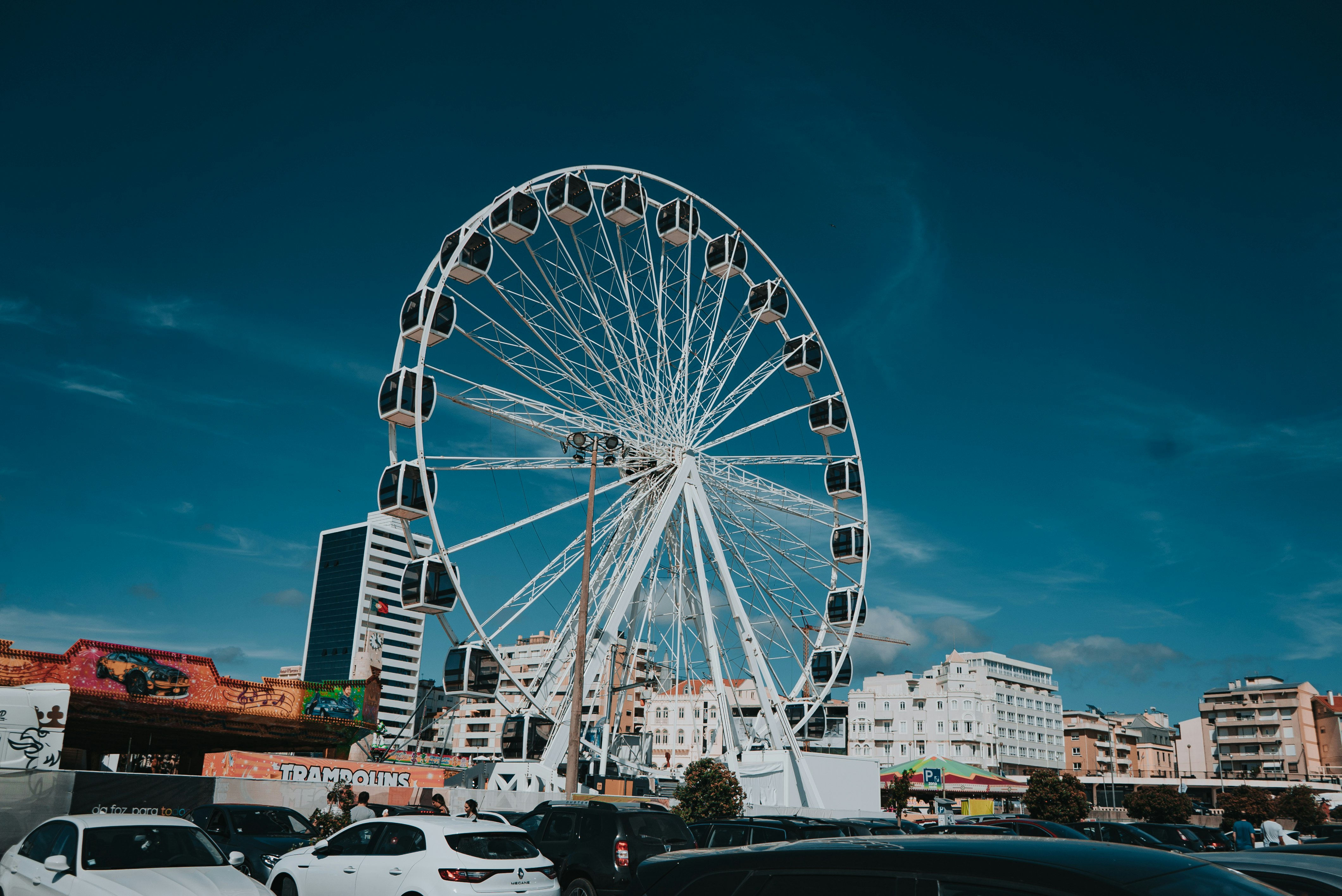 white ferris wheel near white car during daytime