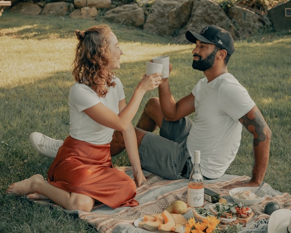 A couple enjoying a picnic with thoughtful gifts around them.