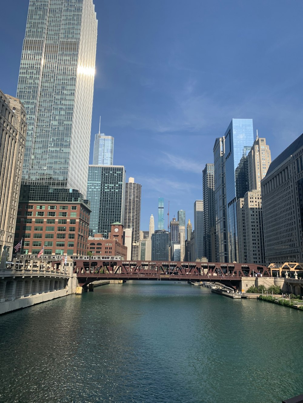 bridge over river between high rise buildings during daytime